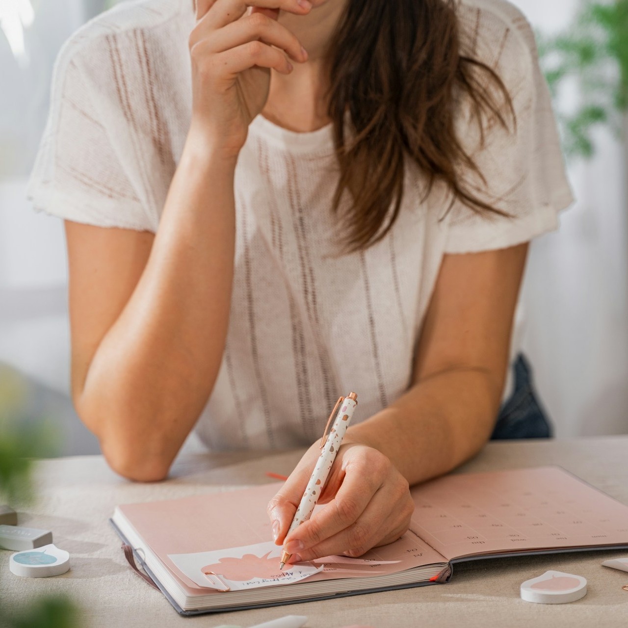 A woman plans a party by writing in a calendar notebook