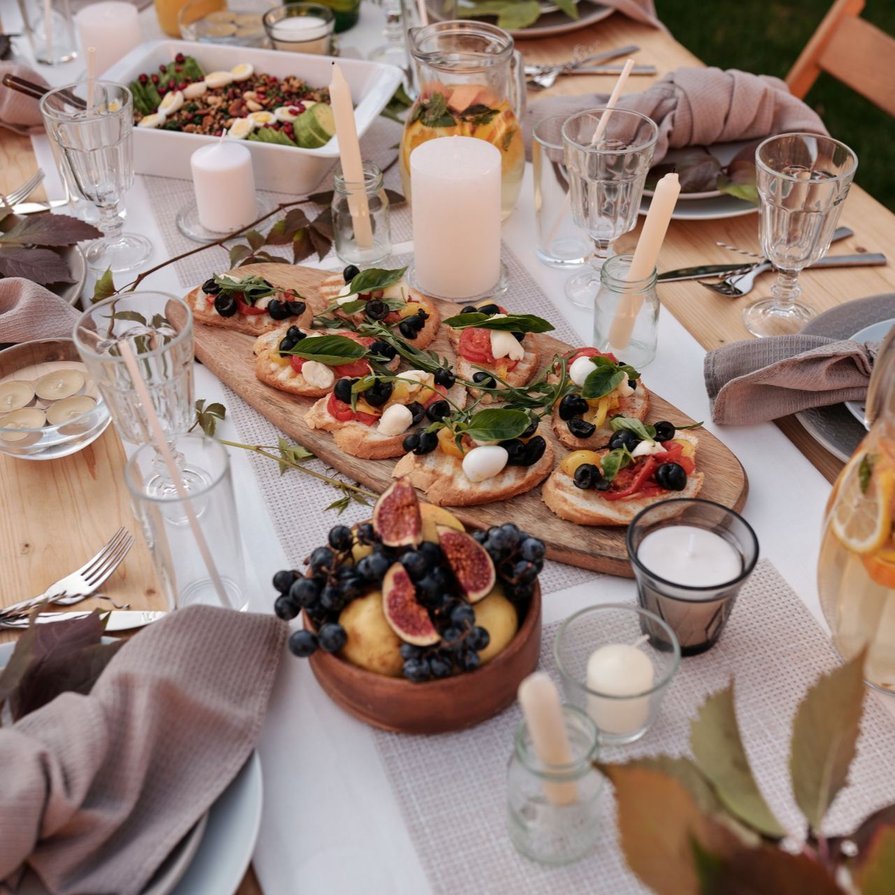 Elegant outdoor table setting with appetizers and candles for a party