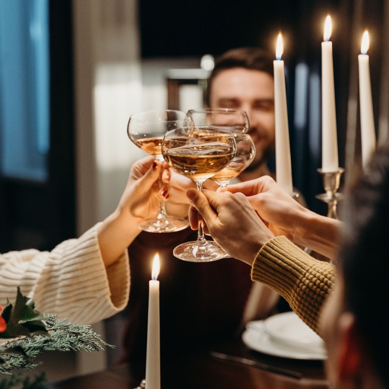 Friends clink glasses in a toast at a candlelit dinner party