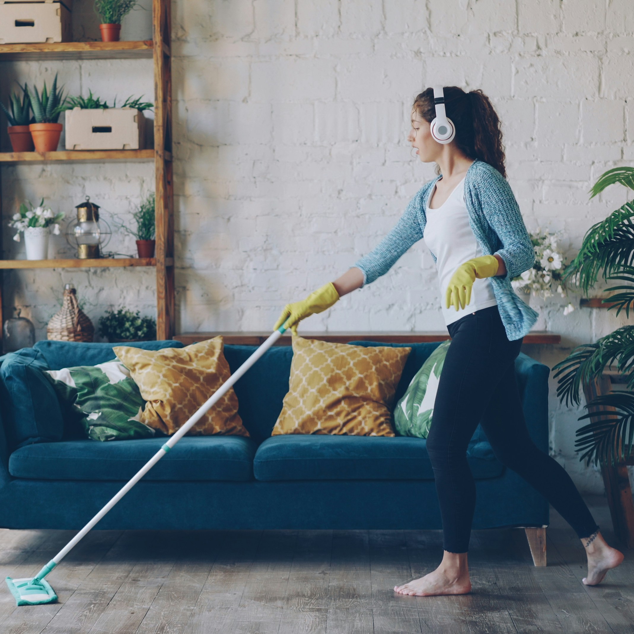 Woman Cleaning Living Room Woman wearing headphones cleans the living room with a mop