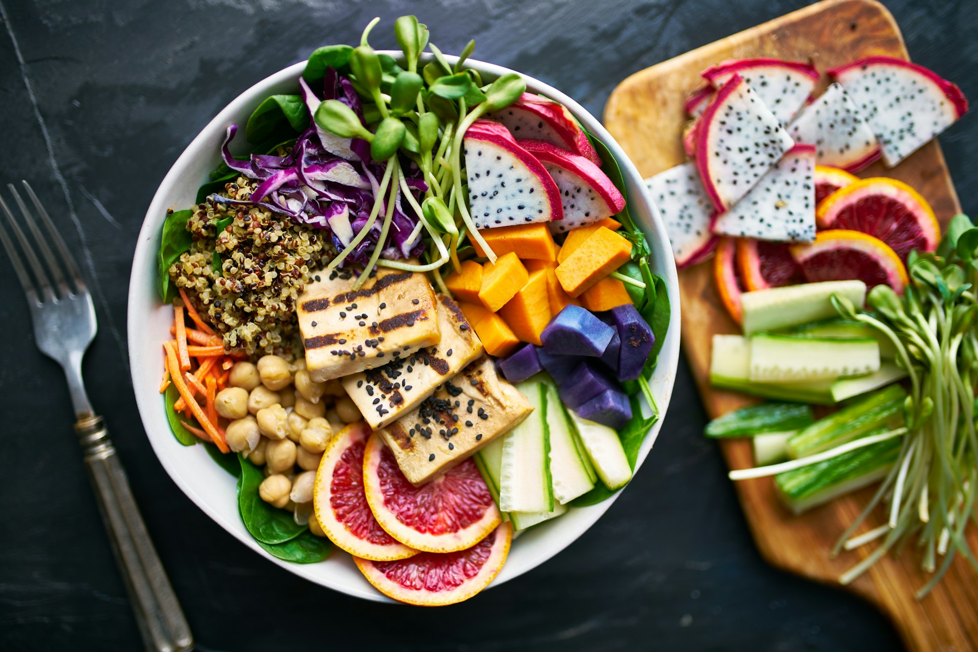 Vibrant Salad Bowl with Tofu Colorful salad bowl with tofu, vegetables, and fruit slices on a dark surface