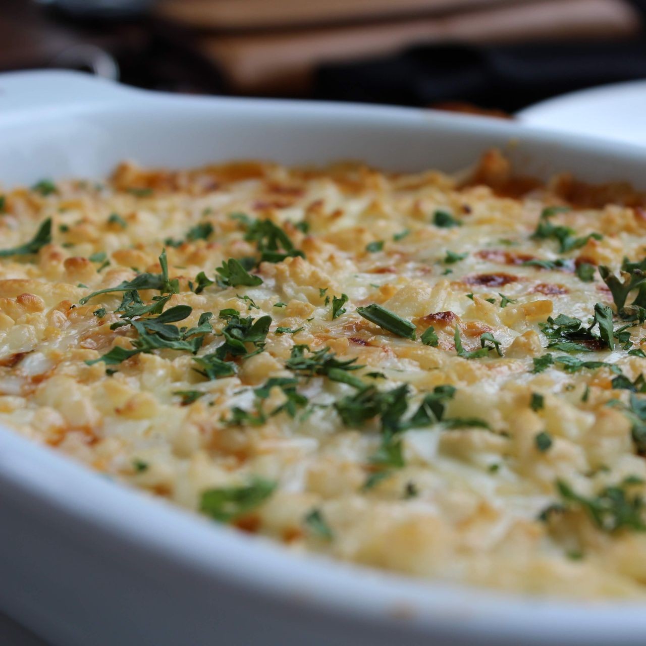 A baked casserole dish topped with fresh herbs, perfect for home entertaining