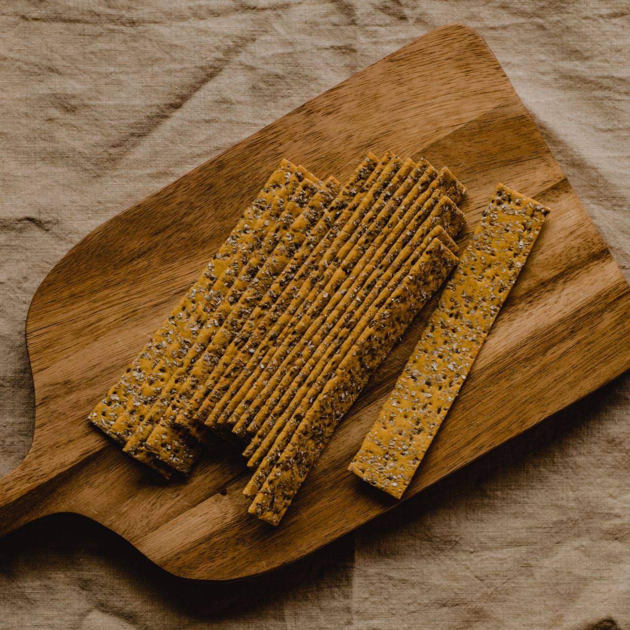Seed Crackers on Wooden Board Crunchy seed crackers are neatly arranged on a wooden serving board.