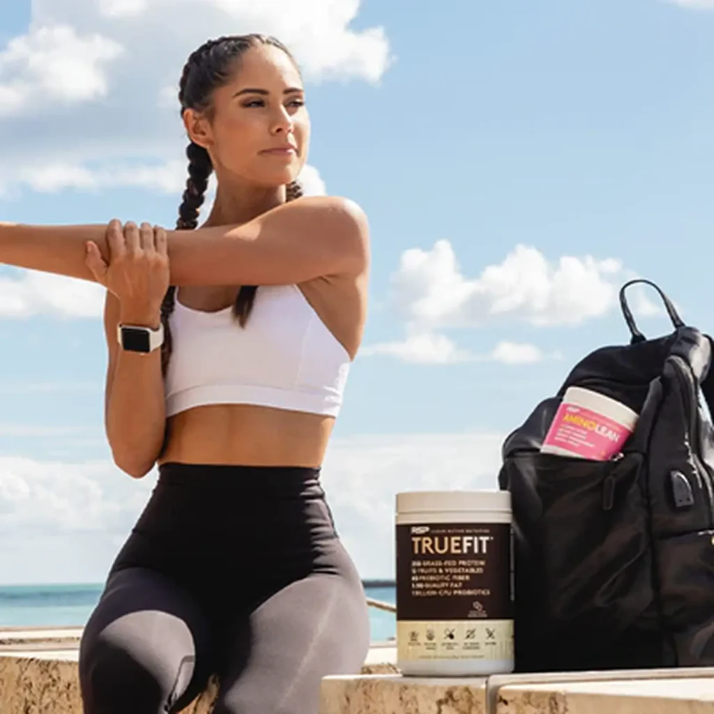 woman stretching her arms sitting on a wall with true fit next to her woman stretching her arms sitting on a wall with true fit next to her
