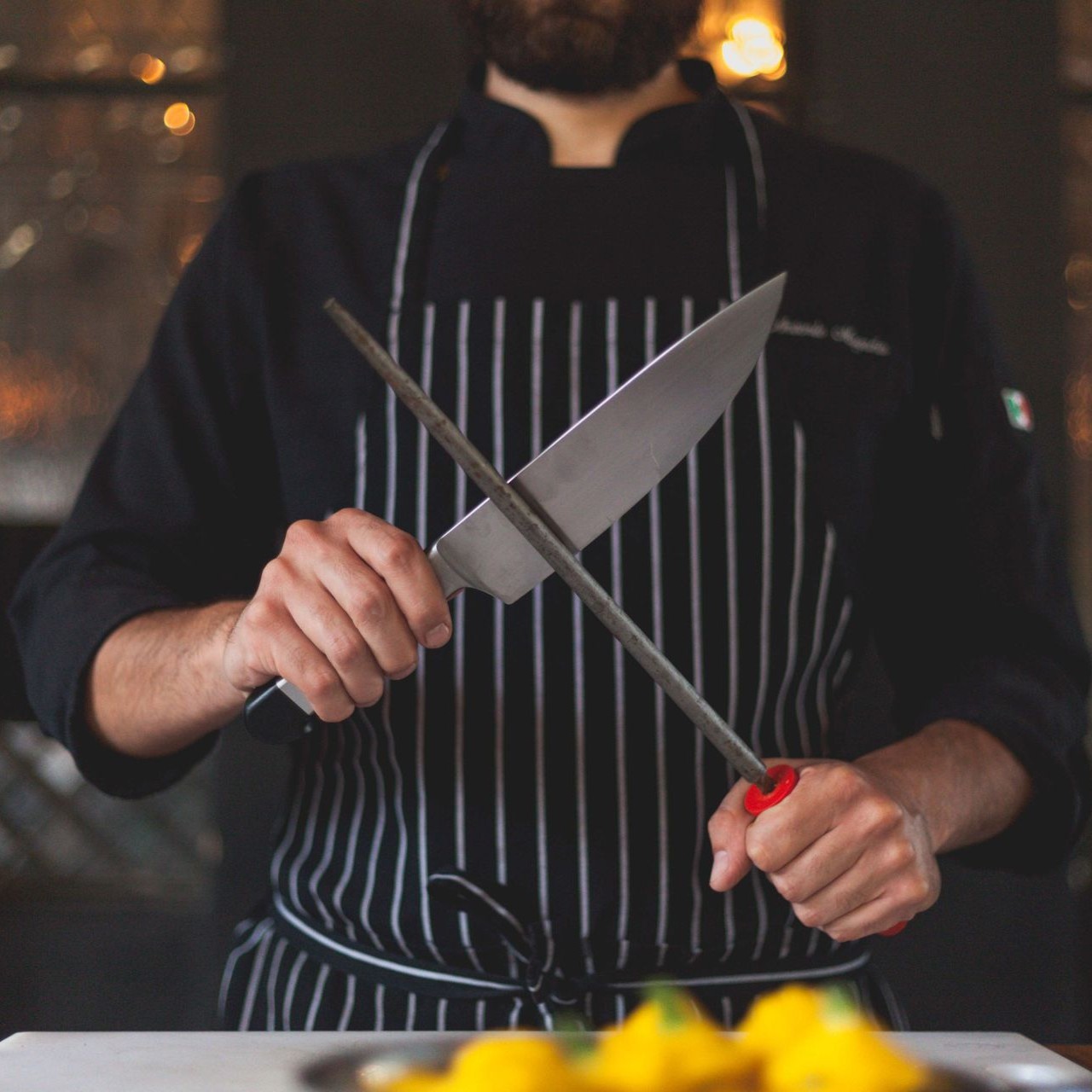 Chef Sharpening Knife Chef sharpens a knife with a honing rod in a kitchen setting