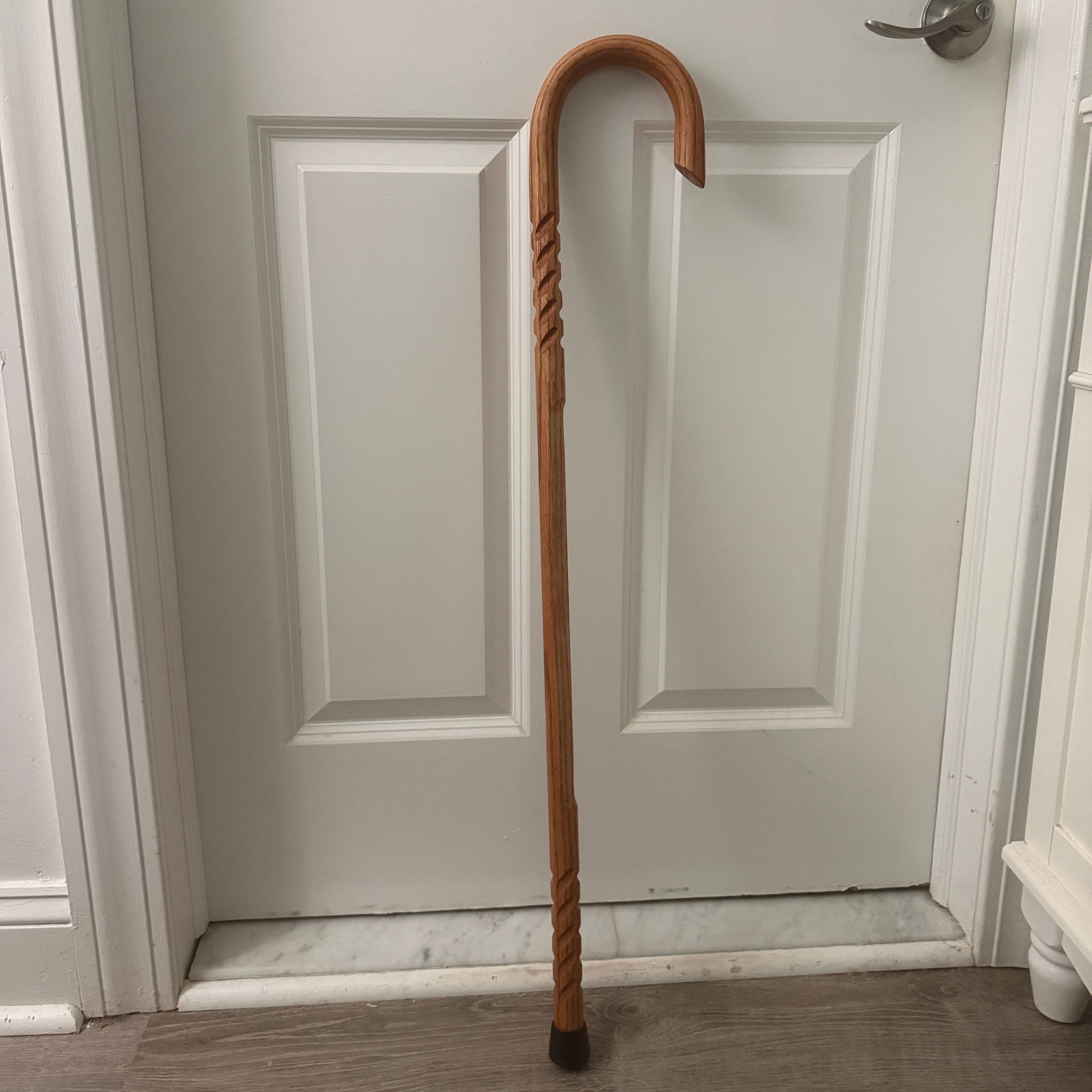 Cane Masters Handcrafted Wooden Cane A Cane Masters handcrafted pure hickory cane with an inside cut horn leans against a white door