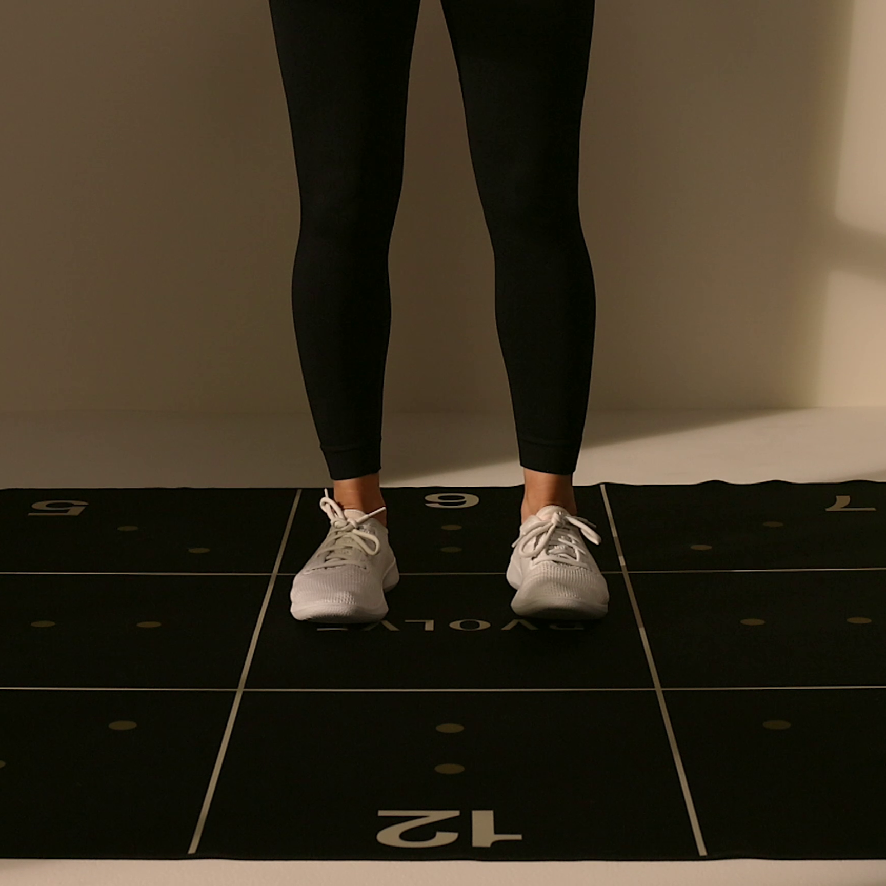 PVOLVE Precision Mat with Person Standing Person stands on a PVOLVE Precision Mat wearing black leggings and white sneakers