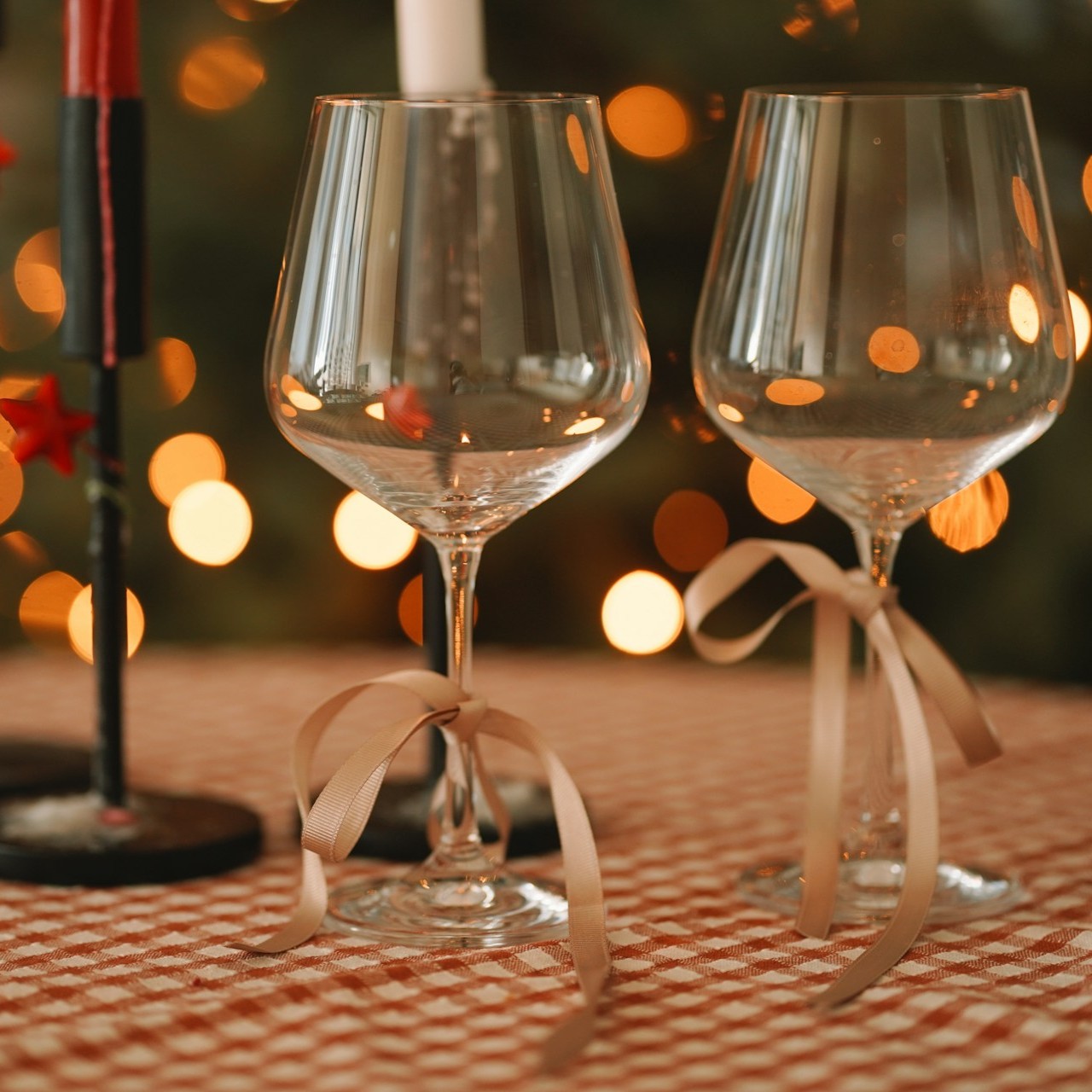 Two empty wine glasses with ribbons sit on a festive table