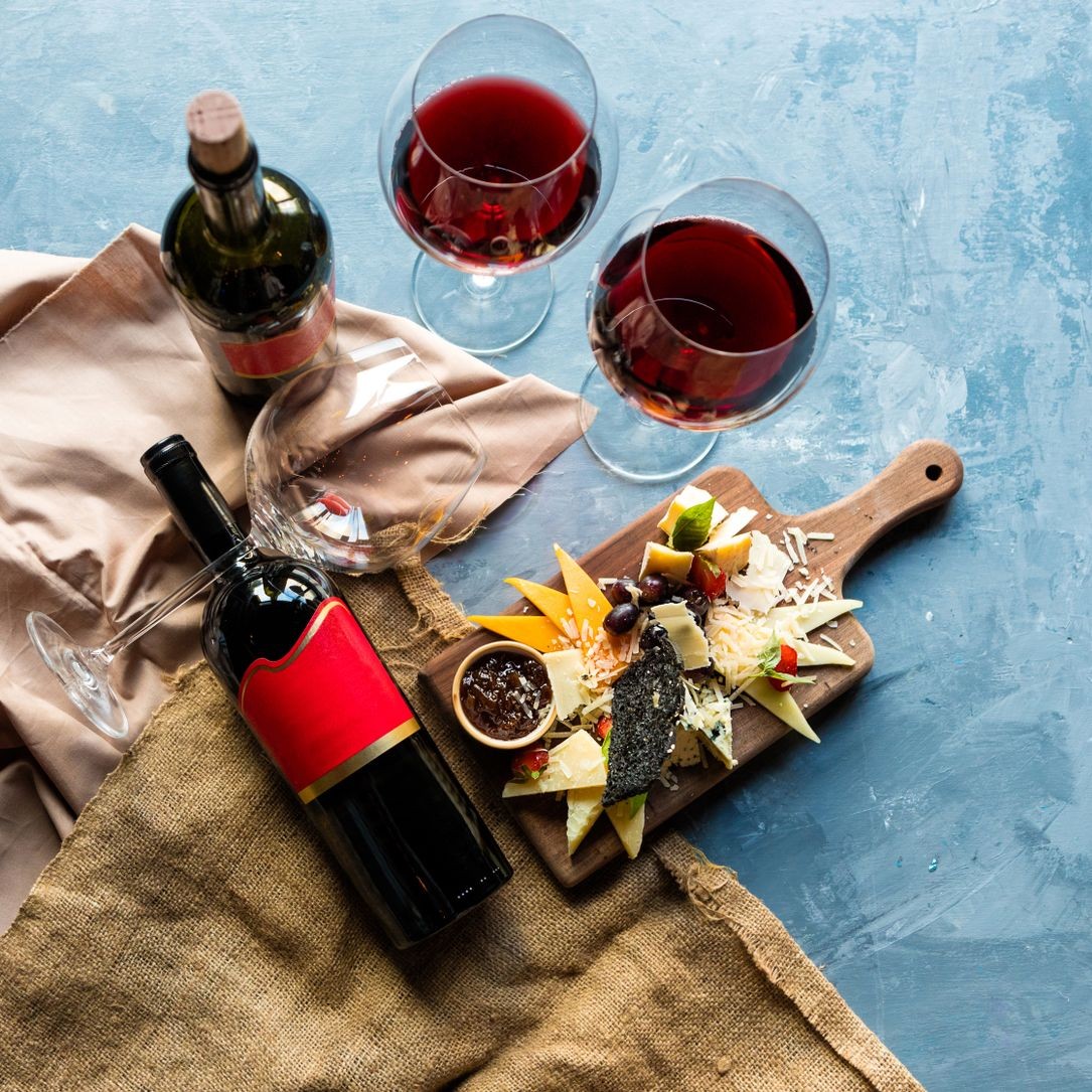 Holiday Wine and Cheese Selection Two glasses of red wine with a cheese platter on a wooden board