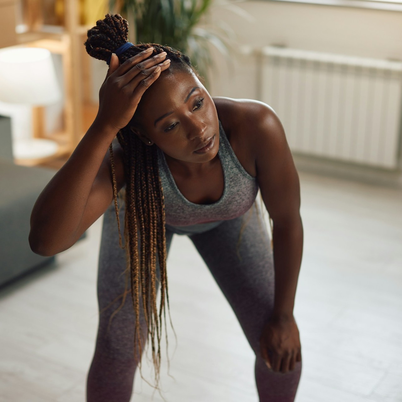 Woman in workout attire rests after exercise in a living room