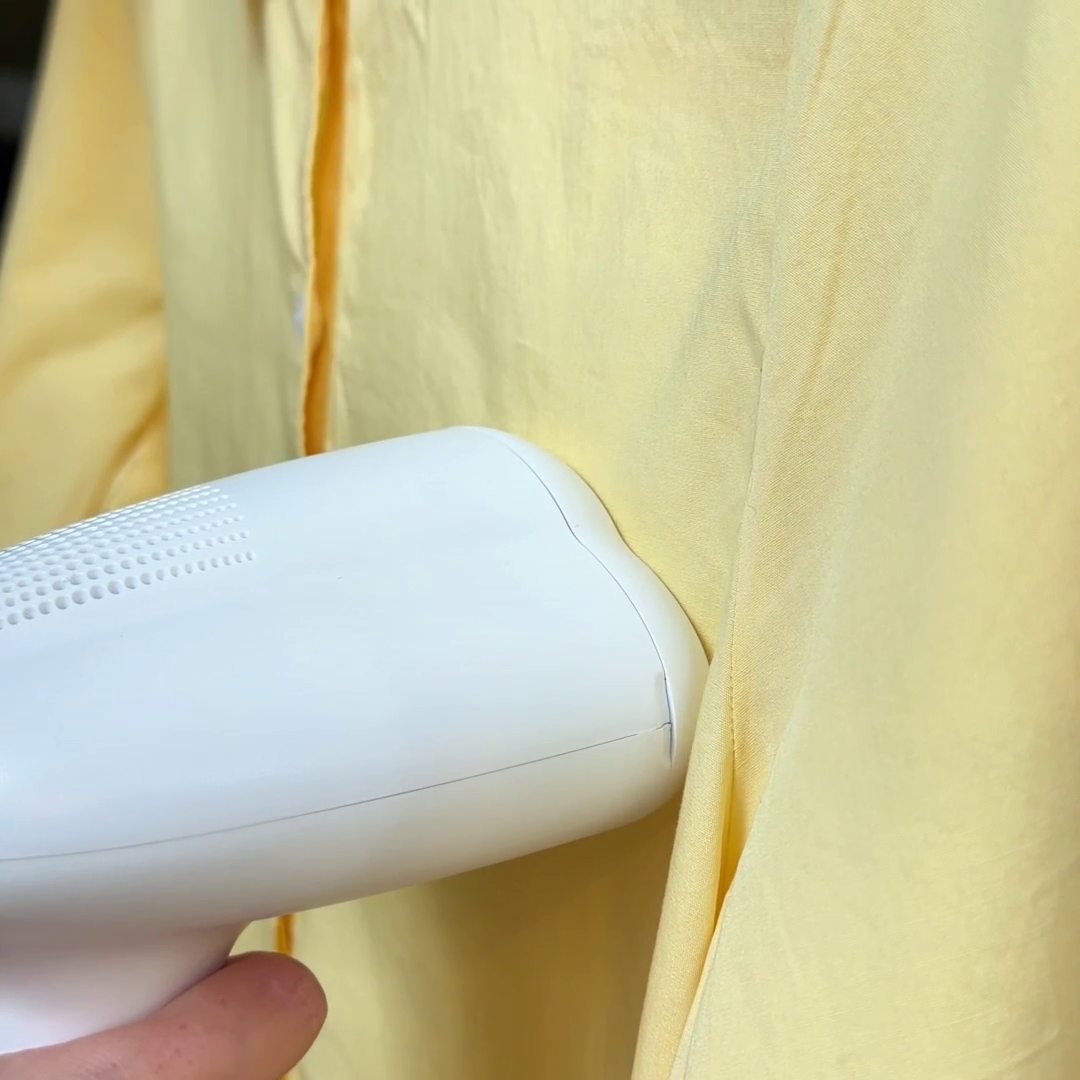 The Nori Cloud Max steamer is used on a yellow shirt to remove wrinkles
