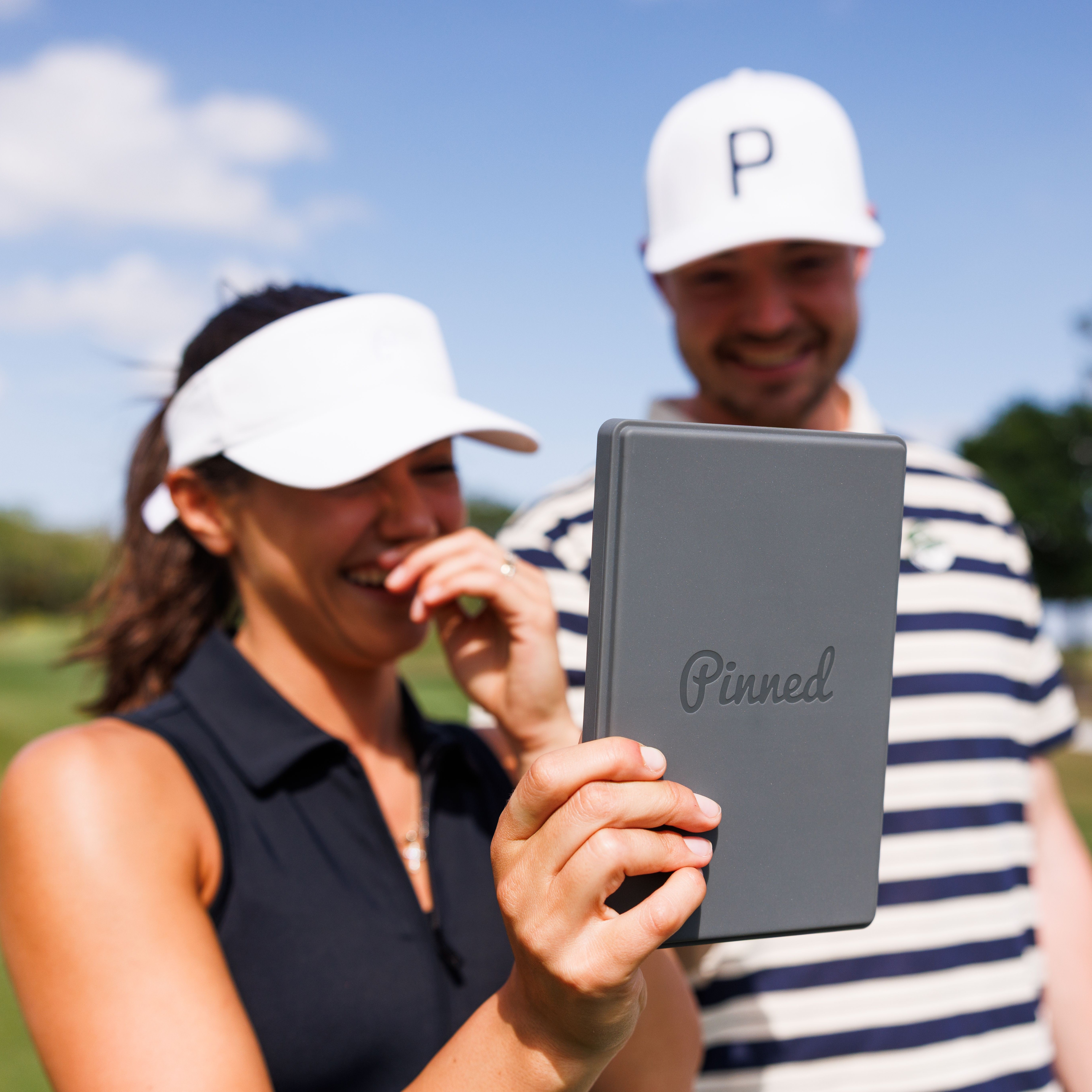 Two golfers smile while using The Caddie GPS tablet on a sunny day